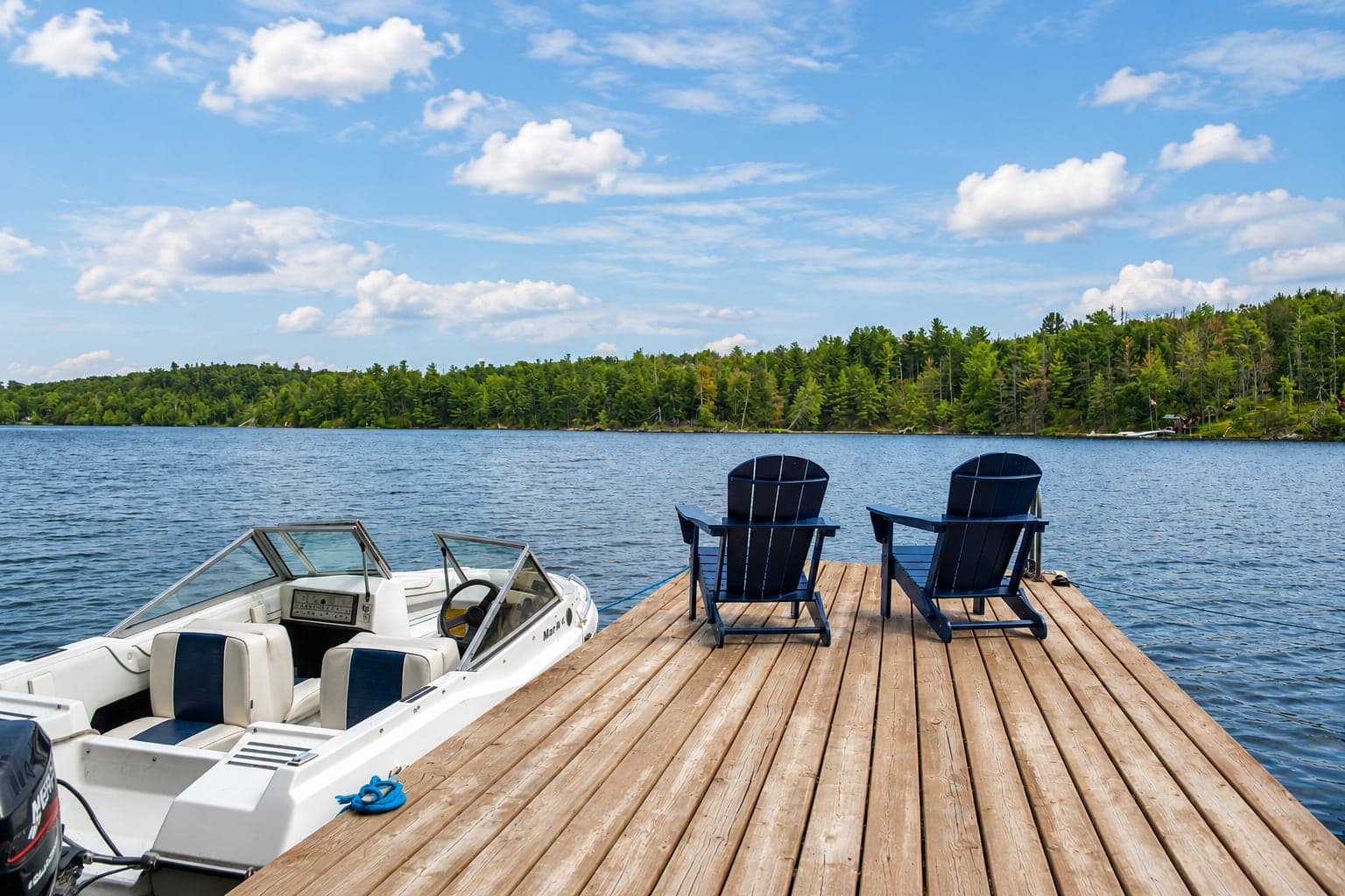 The dock at Birch Island Cottage with chairs, a boat, and Sand Lake beyond